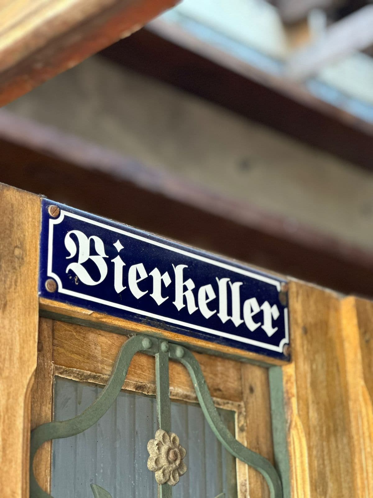 Placa esmaltada azul e branca com a palavra Bierkeller sobre a porta de madeira